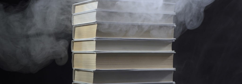 Une pile de livres d’où sort de la fumée, symbolisant le mélange de cigarettes électroniques et d’histoire.