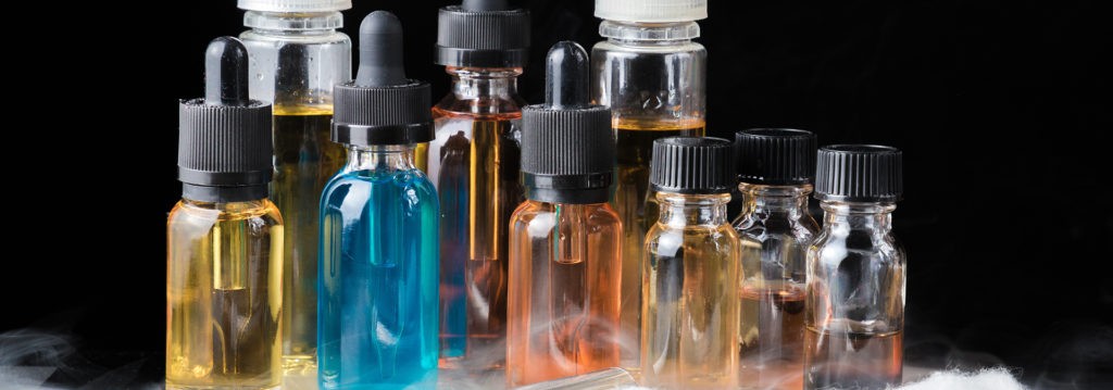 Une composition de bouteilles d'e-liquide de différentes couleurs sur fond noir.