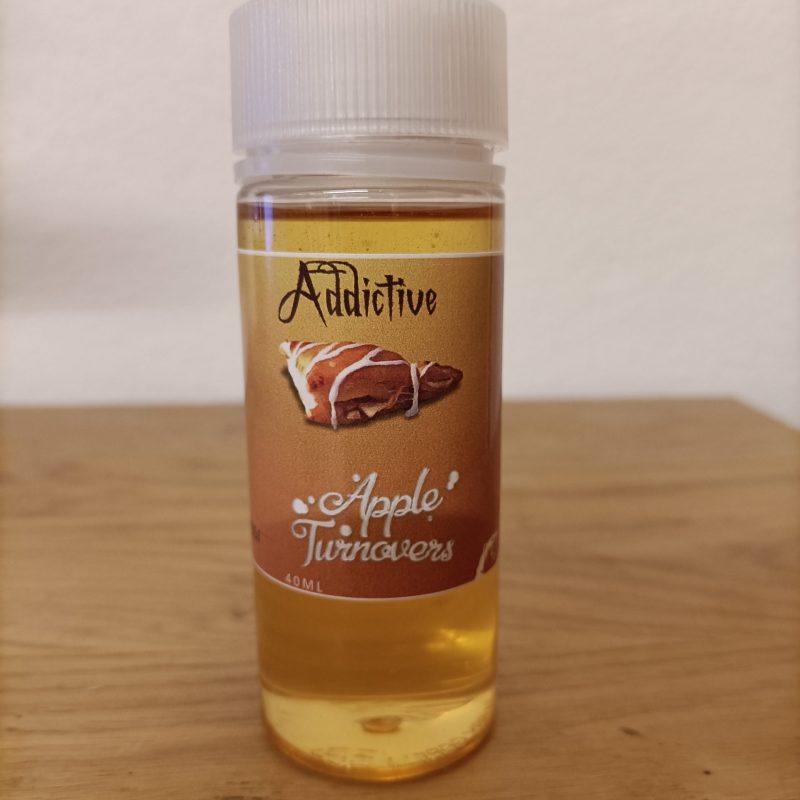 Une bouteille de e-liquide BDY - Apple Turnovers 100ML, présentant l'arôme indulgent des chaussons aux pommes, posée élégamment sur une table.